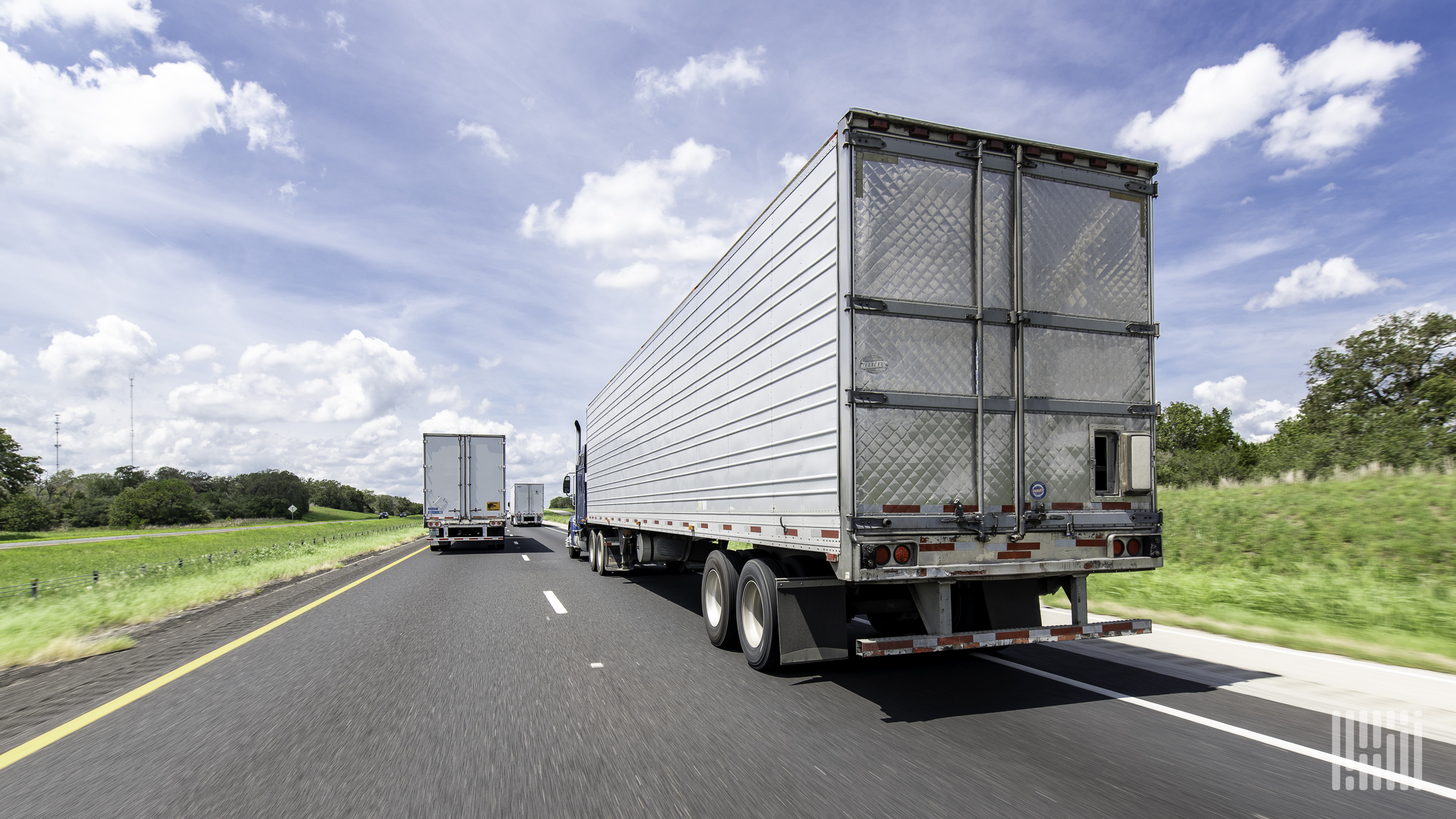 Semi trucks are traveling down a highway.