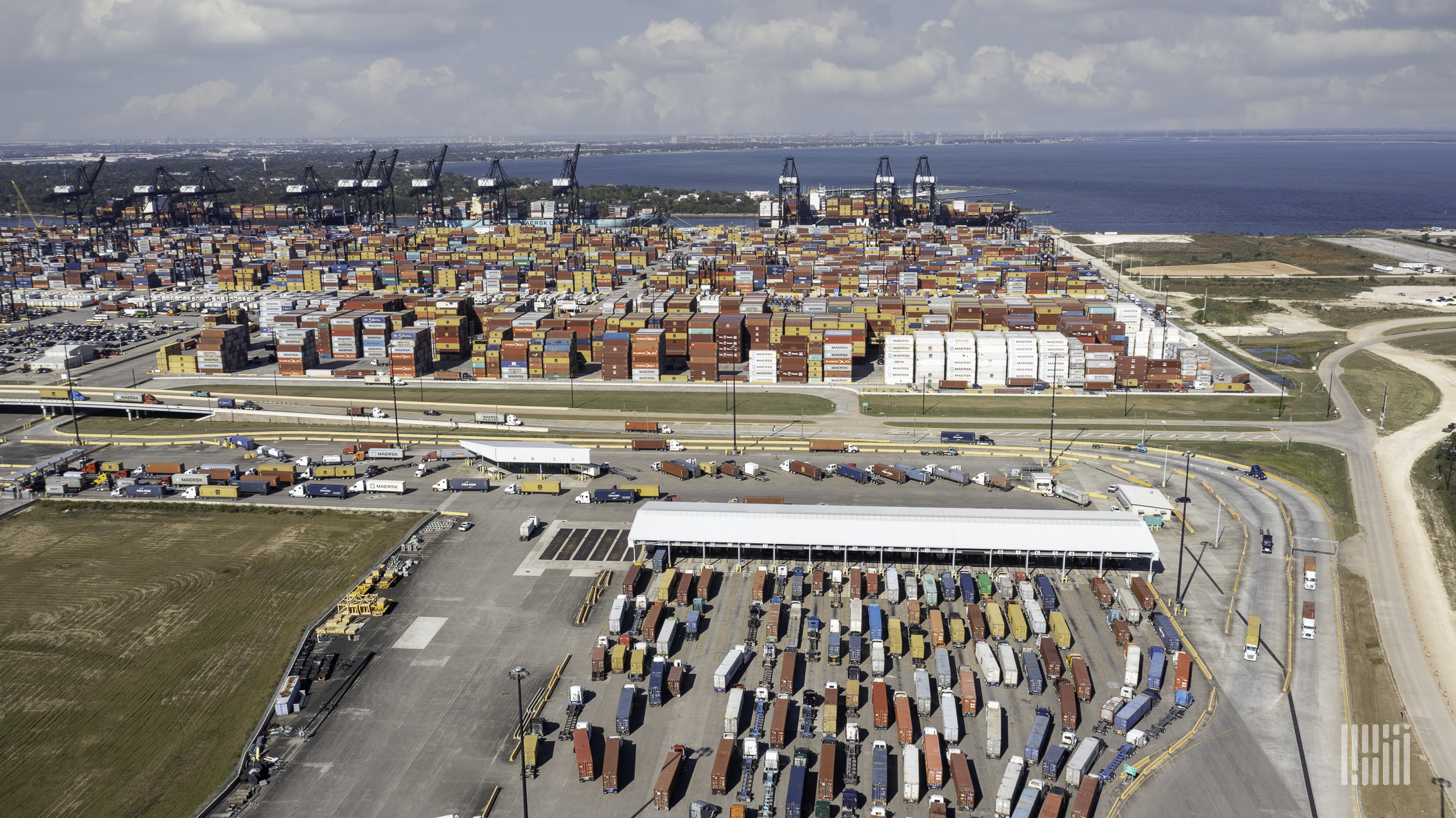 Semi trucks wait in lines to enter a maritime port.