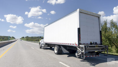 A white delivery truck with liftgate on a highway