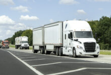 A white tractor pulling two white LTL trailers