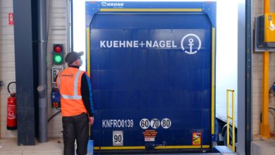 A blue Kuehne + Nagel truck from the rear, backed into a loading dock.