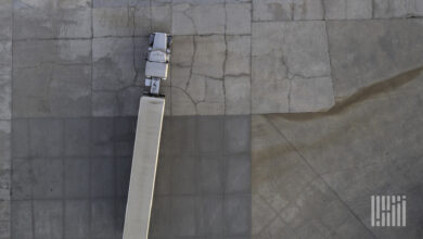 A tractor-trailer is seen from above as it drives in a parking lot.