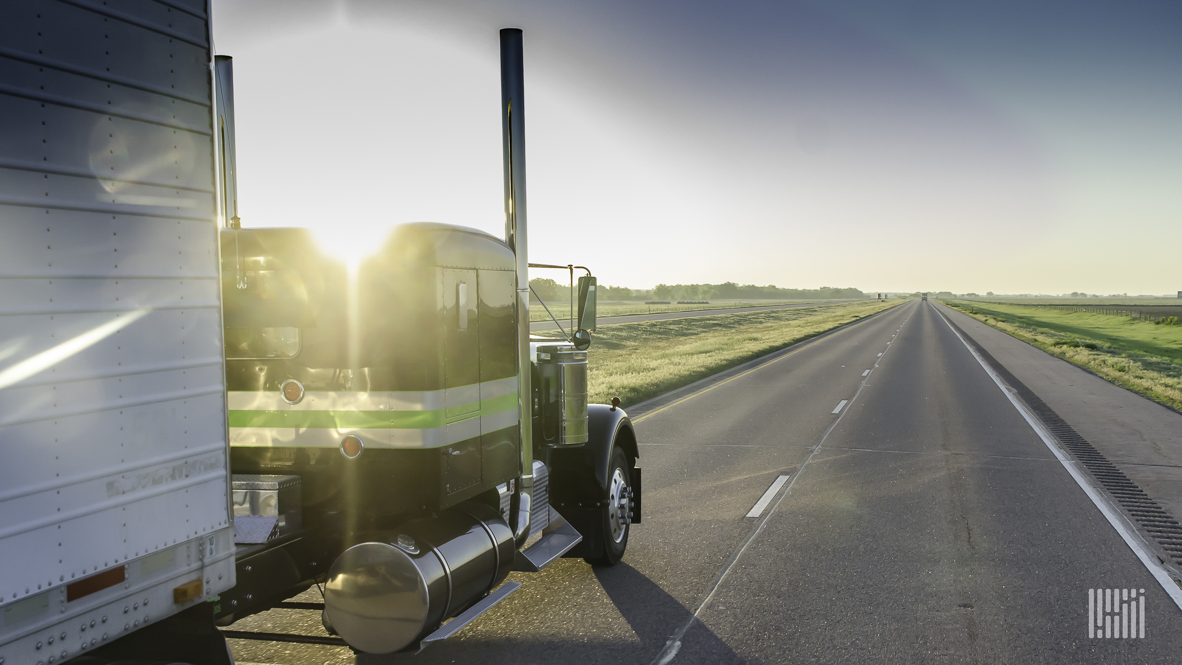 A semi truck on the left travels down the road.